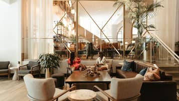 A spacious lobby with a central seating area, a staircase, and a large plant.
