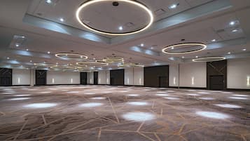 A spacious hall with a polished floor and multiple circular light fixtures on the ceiling.