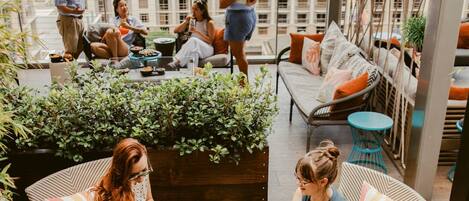A rooftop terrace with outdoor seating, a view of a building labeled 'FOUR SEASONS,' and a variety of plants.