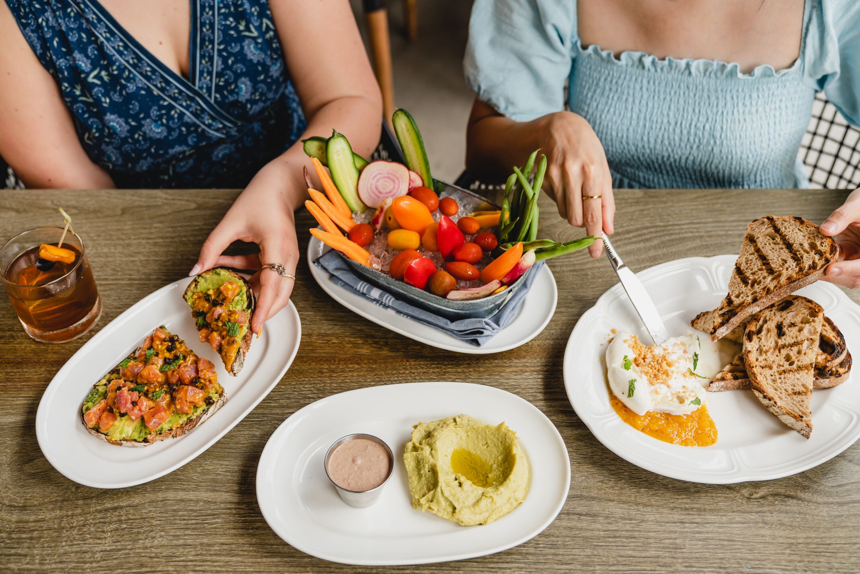 A dining table with various dishes including avocado, toast, and a salad with vegetables.