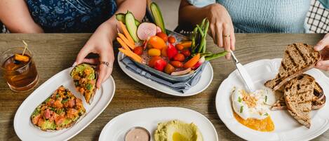 A dining table with various dishes including avocado, toast, and a salad with vegetables.