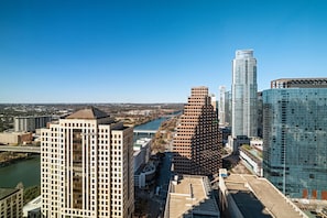A high-rise building with a grid-like facade, a river in the background, and a clear blue sky.