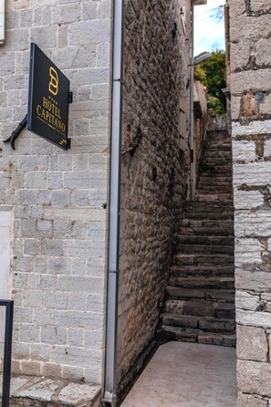 Una estrecha escalera de piedra que conduce a un edificio con un letrero que dice Hotel Capitano.