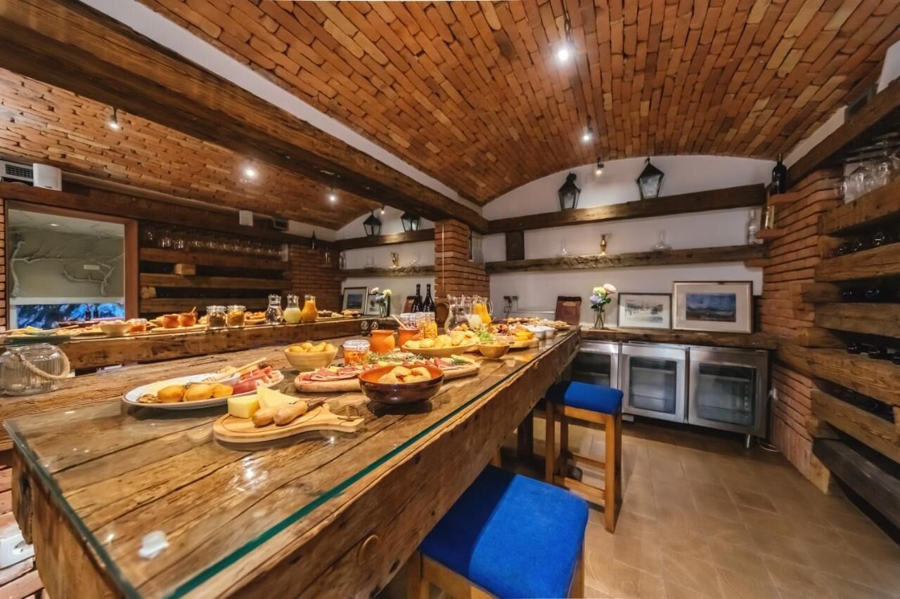 Un long comptoir en bois où sont exposés divers aliments et boissons. On y trouve des étagères remplies de bouteilles et de verres, et un grand miroir est accroché sur le côté gauche.