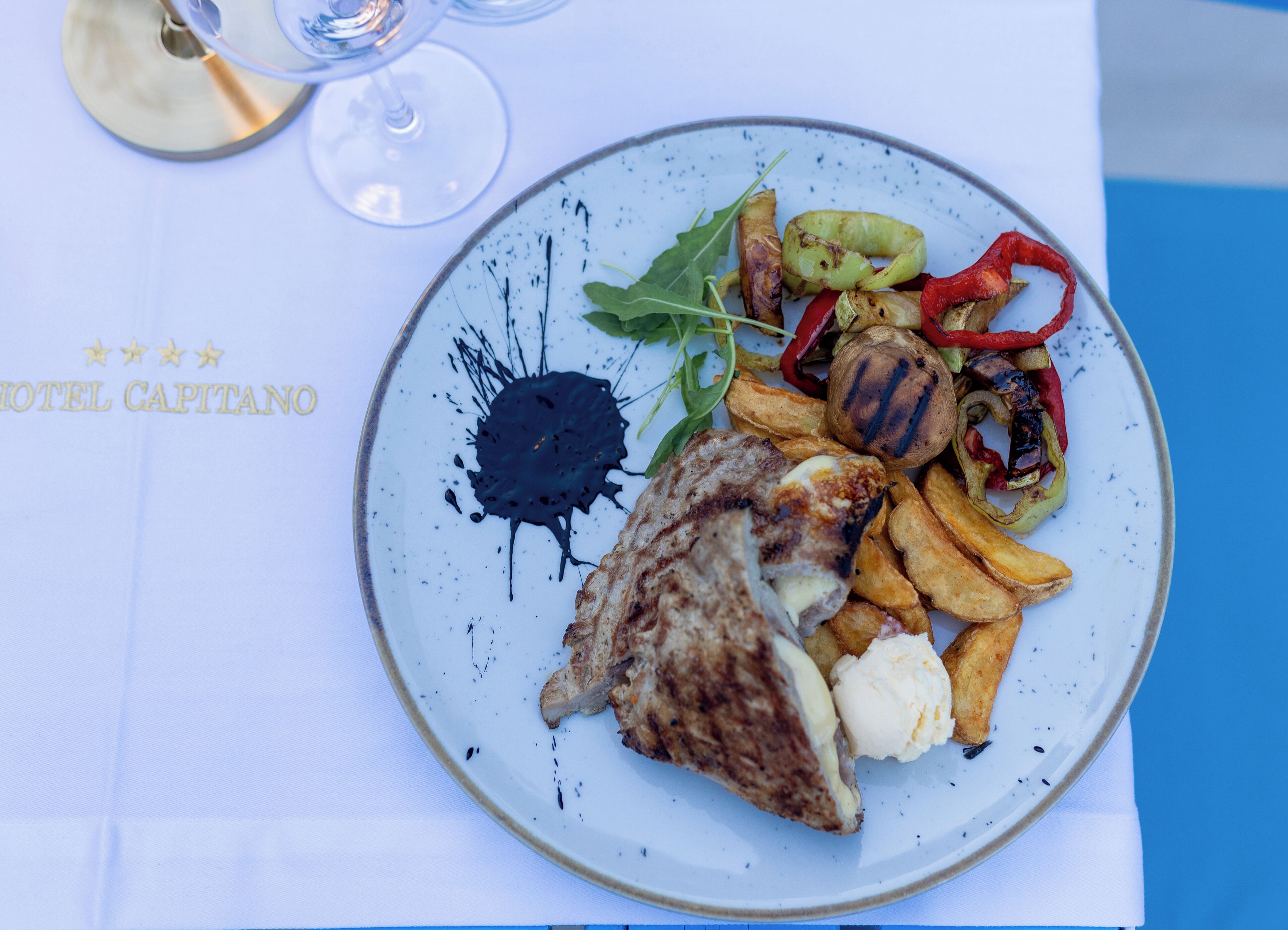 Une assiette de nourriture comprenant un steak, des frites et des légumes, le tout présenté sur une assiette blanche ornée d’un motif bleu.