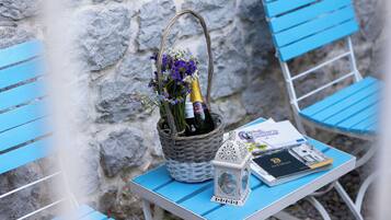 Ein Korbwägelchen mit einer Flasche und Blumen auf einem Tisch, ein Laterne und ein Buch.