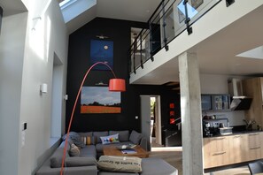 Un salon moderne avec un canapé, une table basse et des œuvres d’art accrochées au mur.