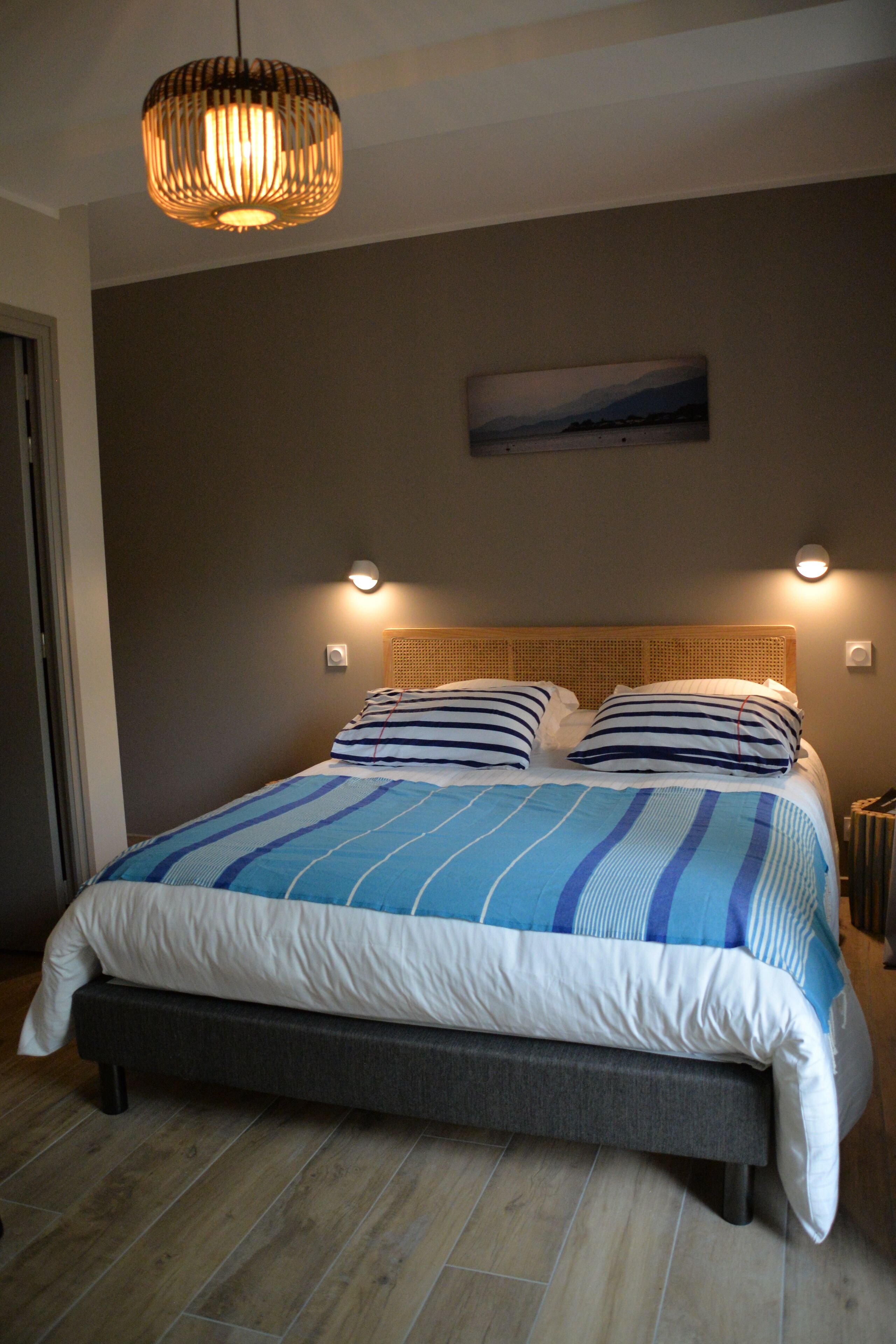 Una camera da letto con un letto, un lampadario a sospensione e un quadro appeso al muro.