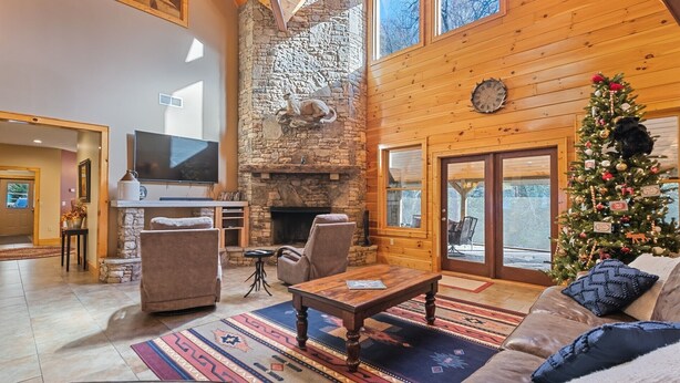 A cozy living room with a stone fireplace, a large TV, and a Christmas tree.