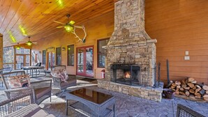 A cozy lodge with a stone fireplace, wicker furniture, and a ceiling fan.