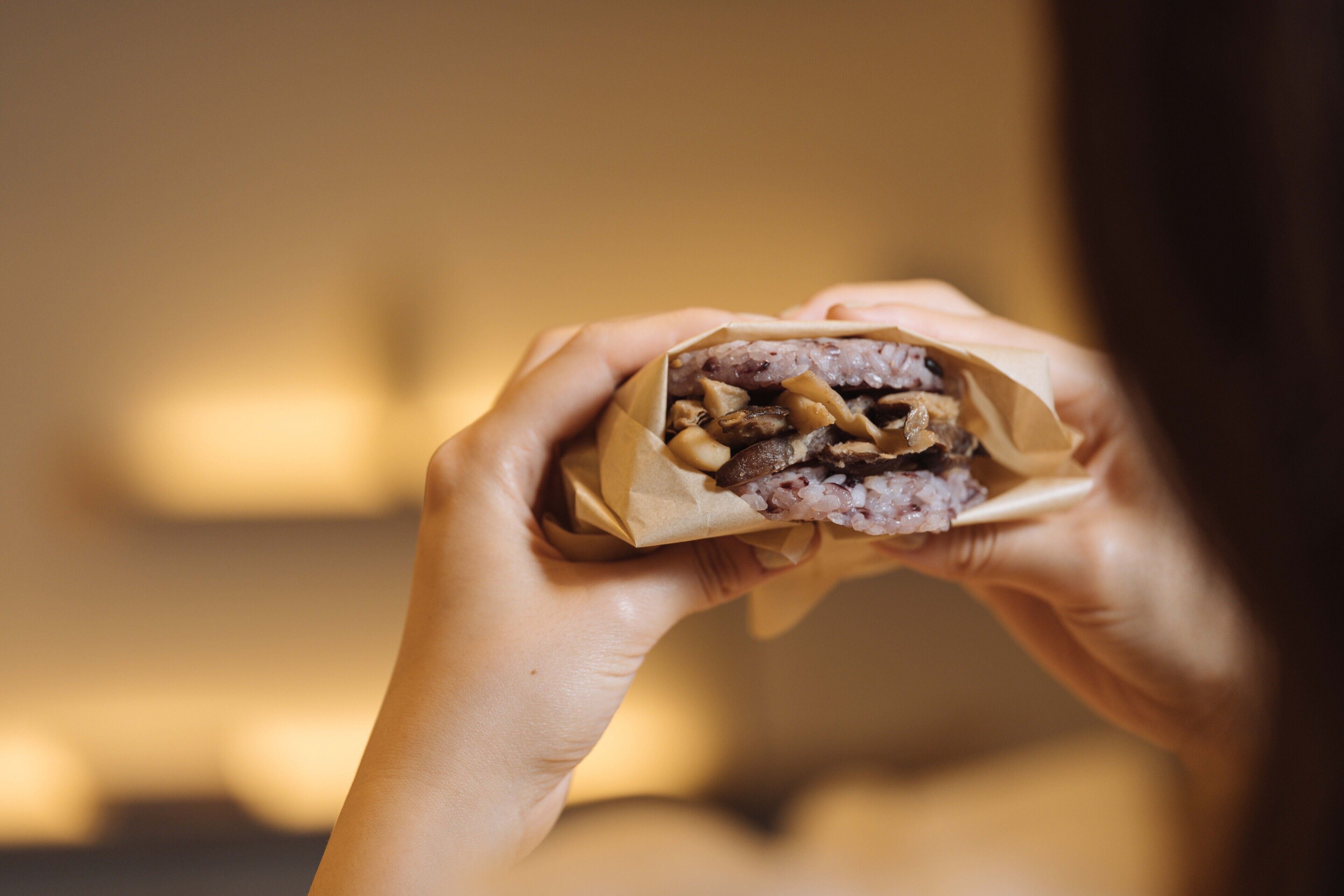 Une personne tenant un sandwich dont on peut voir les ingrédients.