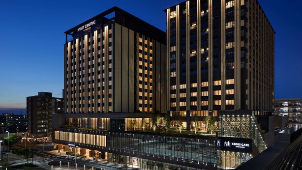 Un hôtel moderne, doté de plusieurs étages, d’une entrée imposante et d’une façade bien éclairée.