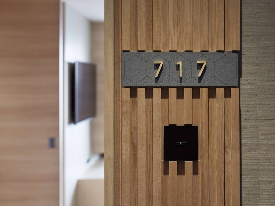 Un mur en bois sur lequel est fixée une plaque portant le numéro « 717 », et en dessous, un petit objet carré de couleur noire.