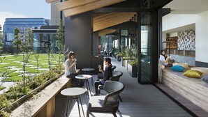 Un espace extérieur aménagé avec des tables et des chaises, une terrasse en bois et une vue sur le paysage urbain.