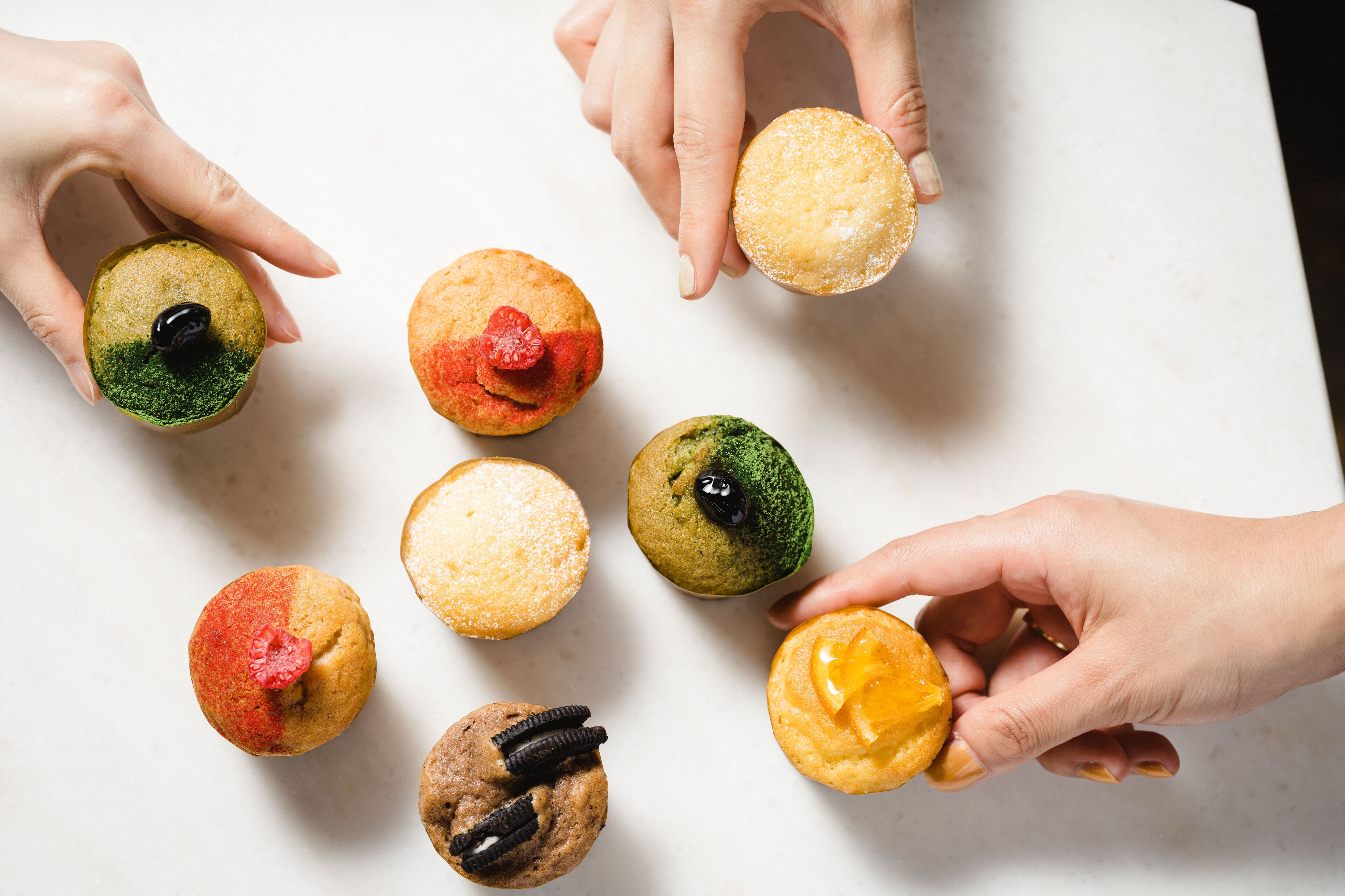 A variety of cupcakes with different toppings and colors.