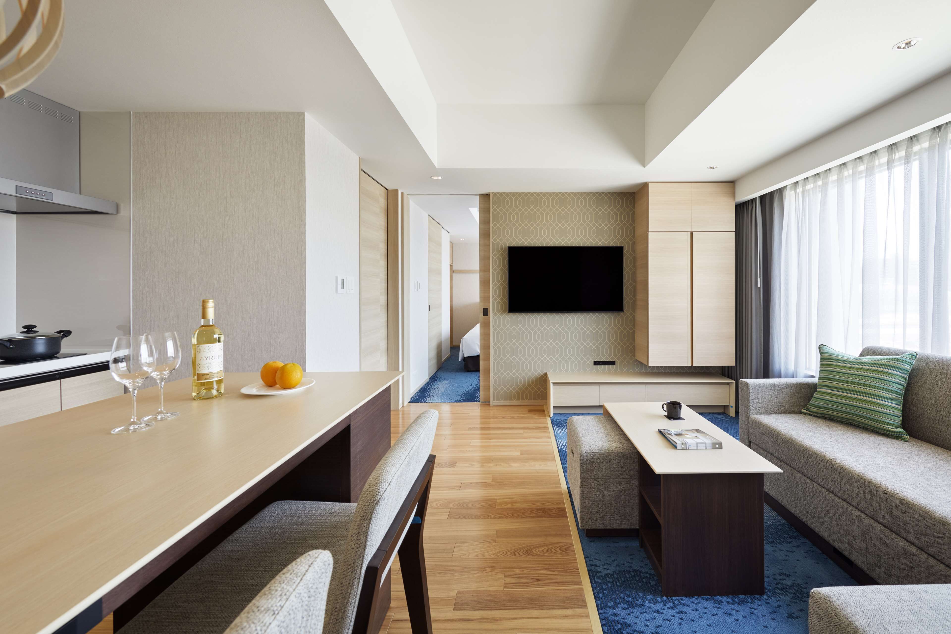 Een moderne hotelkamer met een zithoek, een bank, een flatscreen televisie en een kitchenette.