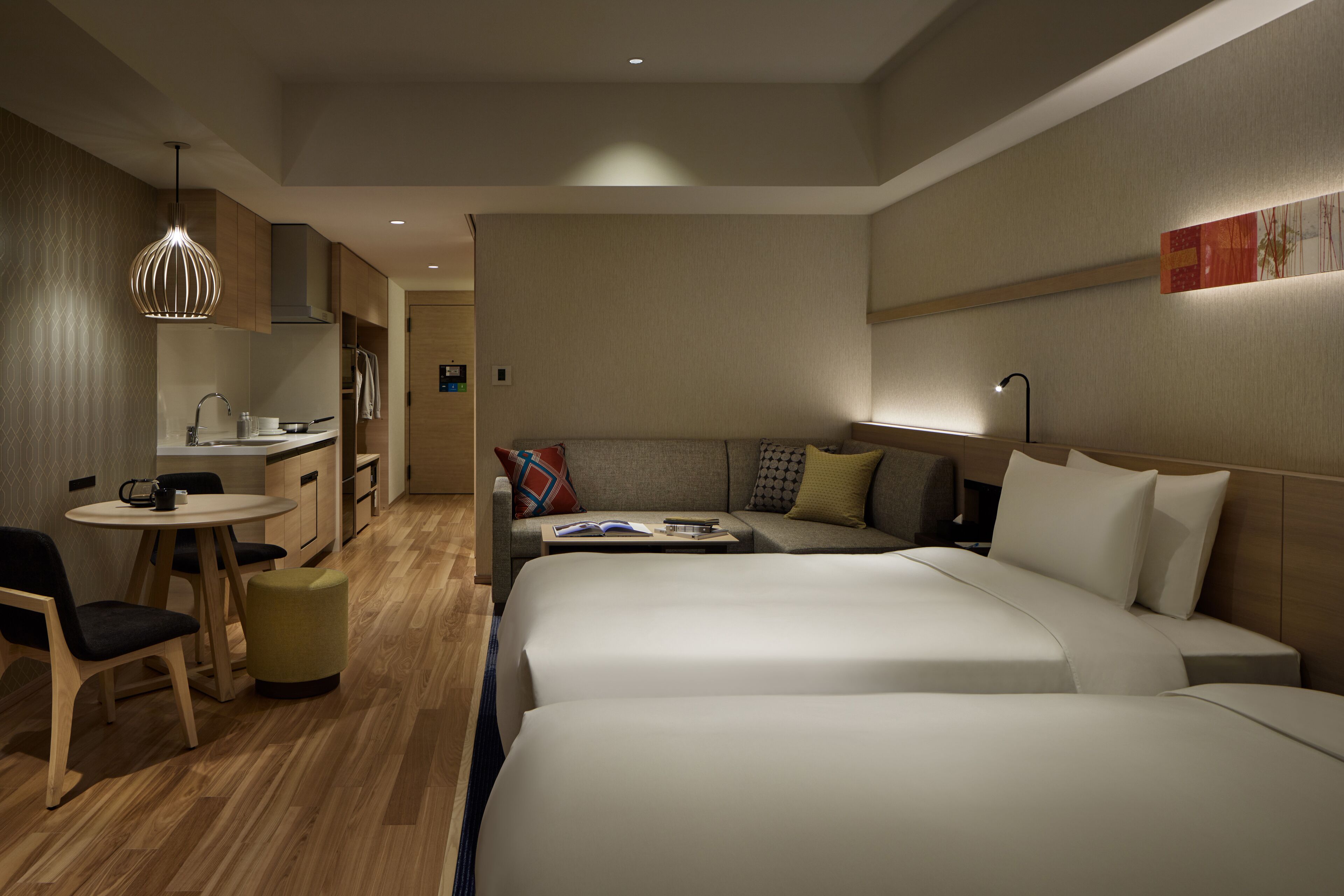Une chambre d’hôtel moderne avec deux lits, un coin repas et une kitchenette.
