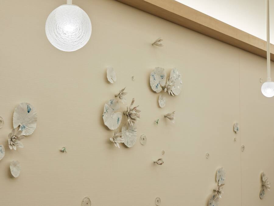 Una pared decorada con flores de papel y una lámpara colgante.