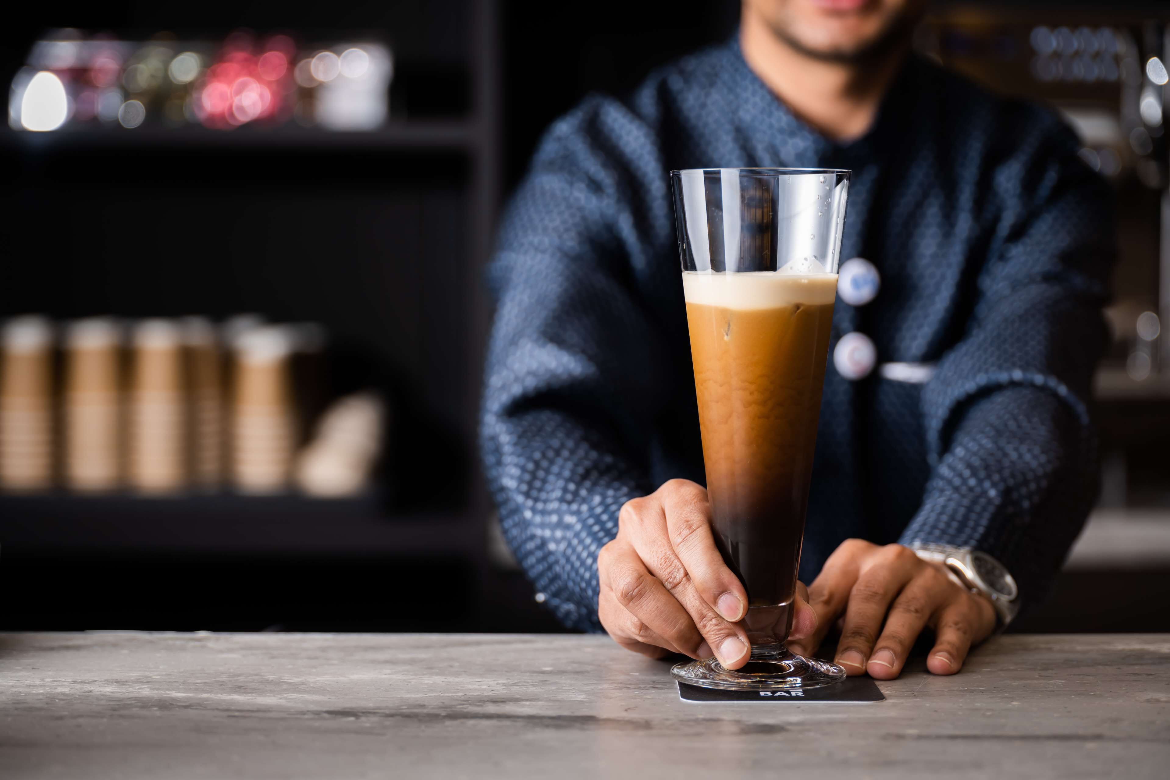 Une personne tenant un grand verre de bière au bar.
