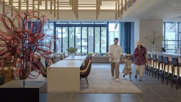 A modern interior with a dining area, a large abstract sculpture, and a view through large windows.