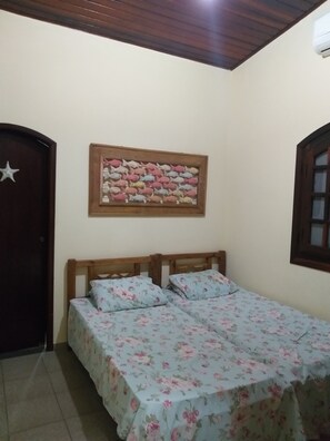 A bedroom with two beds, a wooden headboard, a wall-mounted artwork, and a door with a star decoration.
