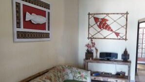 A living room with a sofa, a television on a stand, and decorative wall art.