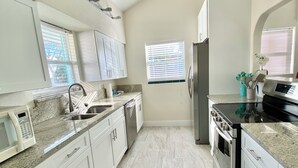 Eine moderne Küche mit weißen Schränken, Granit Arbeitsplatten, einem Edelstahlkühlschrank und einem Einbauofen.
