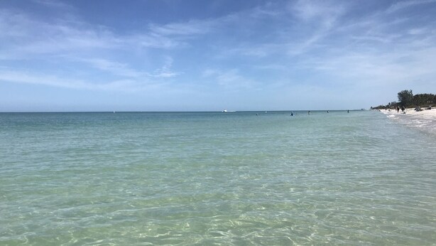 Ein Strand mit klarem, flachen Wasser und einer entfernten Küste.