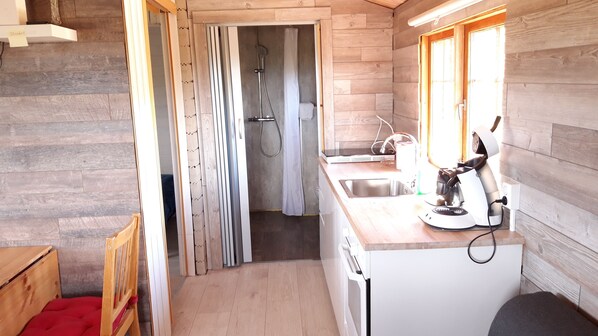 Compact kitchen with sink, coffee maker, and bathroom access.