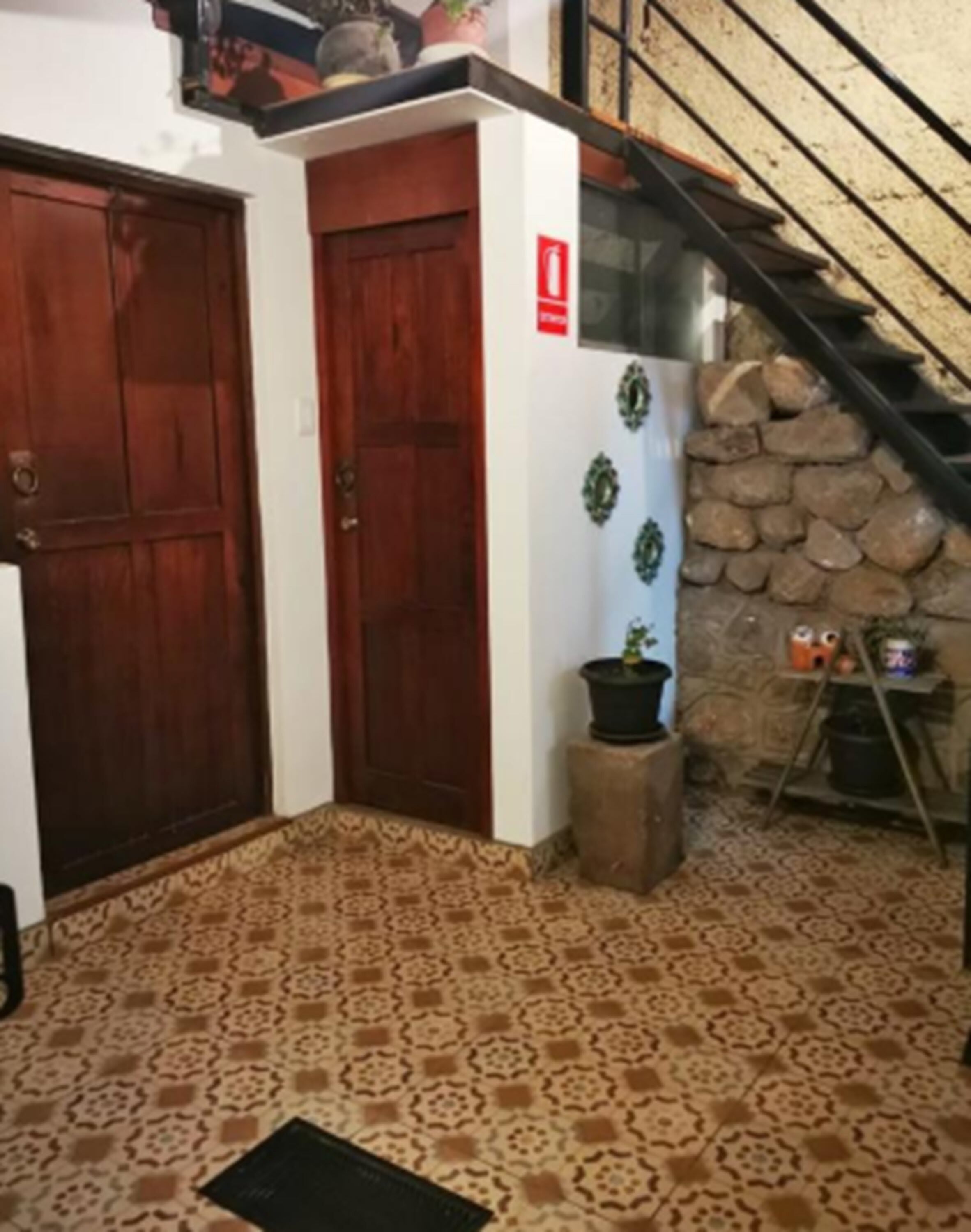 A hallway with patterned flooring, a wooden door, and a staircase with a stone wall.