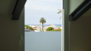 Blick aus einem Fenster auf ein Wohngebiet mit Häusern und einer Palme.
