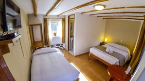 A bedroom with a bed, a chair, a TV, and a window with curtains.
