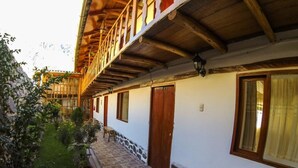 A traditional building with a wooden balcony, stone steps, and a garden area.