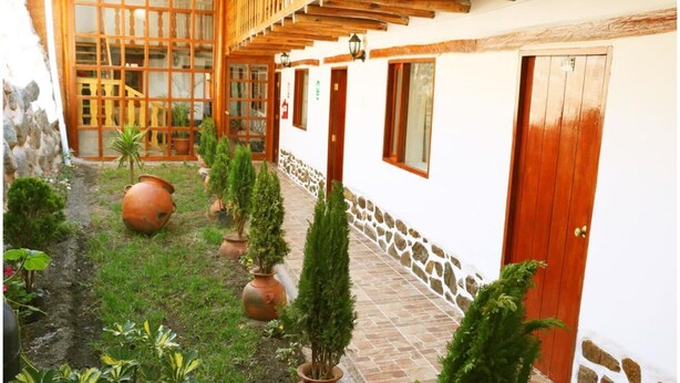 A courtyard with a stone pathway, potted plants, and a wooden pergola.