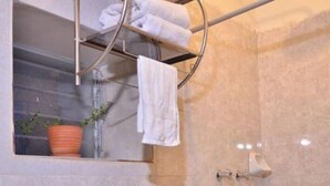 A bathroom with a sink, toilet, shower, and a towel rack with towels.