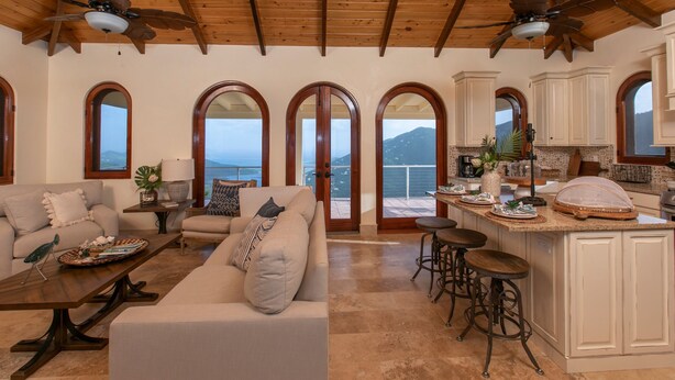A spacious living area with a large sofa, a coffee table, and a kitchen area with bar stools. - Bayview Villa Mint condition, private pool, amazing views. Relaxing breezes! (St.John)