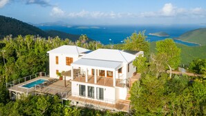 A white two-story house with a pool, surrounded by lush greenery and overlooking a coastal view. - Bayview Villa Mint condition, private pool, amazing views. Relaxing breezes! (St.John)