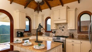 A kitchen with a large island, white cabinetry, and a view of the mountains. - Bayview Villa Mint condition, private pool, amazing views. Relaxing breezes! (St.John)