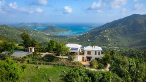 A hillside property with a white house, solar panels, and a view of the sea. - Bayview Villa Mint condition, private pool, amazing views. Relaxing breezes! (St.John)