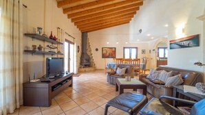 A spacious living room with a fireplace, a television, and a dining area with chairs and a table.