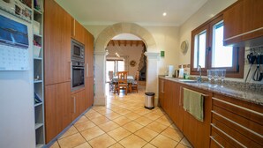 A kitchen with wooden cabinets, a tiled floor, and a dining area with a table and chairs.