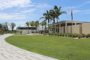A modern building with a flat roof, surrounded by a well-maintained lawn and palm trees. - Our House at the Beach Lakeside (Siesta Key)