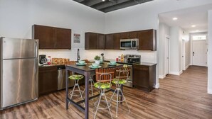 Una cocina moderna con electrodomésticos de acero inoxidable, armarios de madera y una isla central con taburetes de bar.