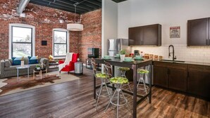 Una cocina moderna con pared de ladrillo, armarios de madera y una zona de comedor con taburetes.