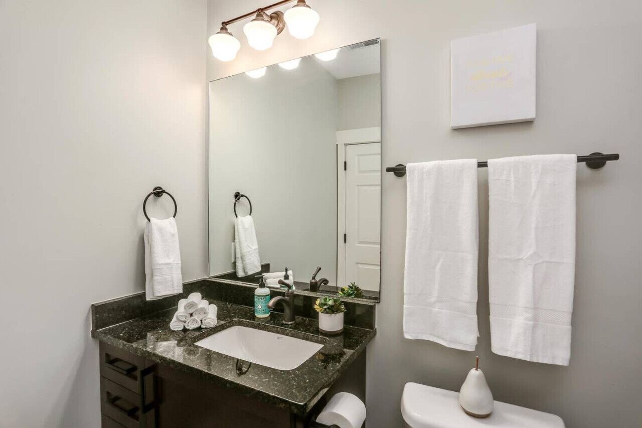 Un bagno con uno specchio grande, un lavabo, un water e due asciugamani su un portasciugamani.