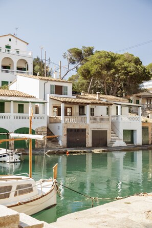 Un edificio costero con balcón, una escalera y un barco amarrado en el agua.