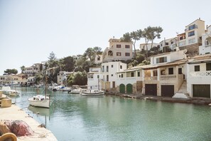 Un pueblo costero con edificios a lo largo del frente marítimo, barcos amarrados y un cielo despejado.