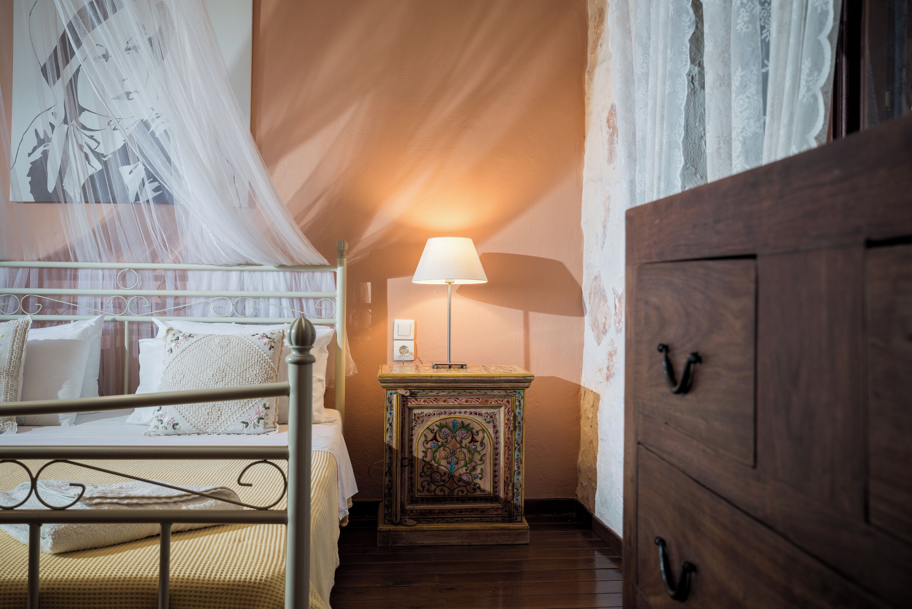 A bedroom with a bed, a bedside table with a lamp, and a wardrobe.