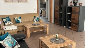 Un salon moderne avec un canapé, deux tables basses et une cuisine en arrière-plan.