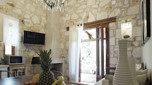 Interior rústic de pedra amb sostre de fusta, un candelabrum, un plat de fruita i un vas blanc únic.